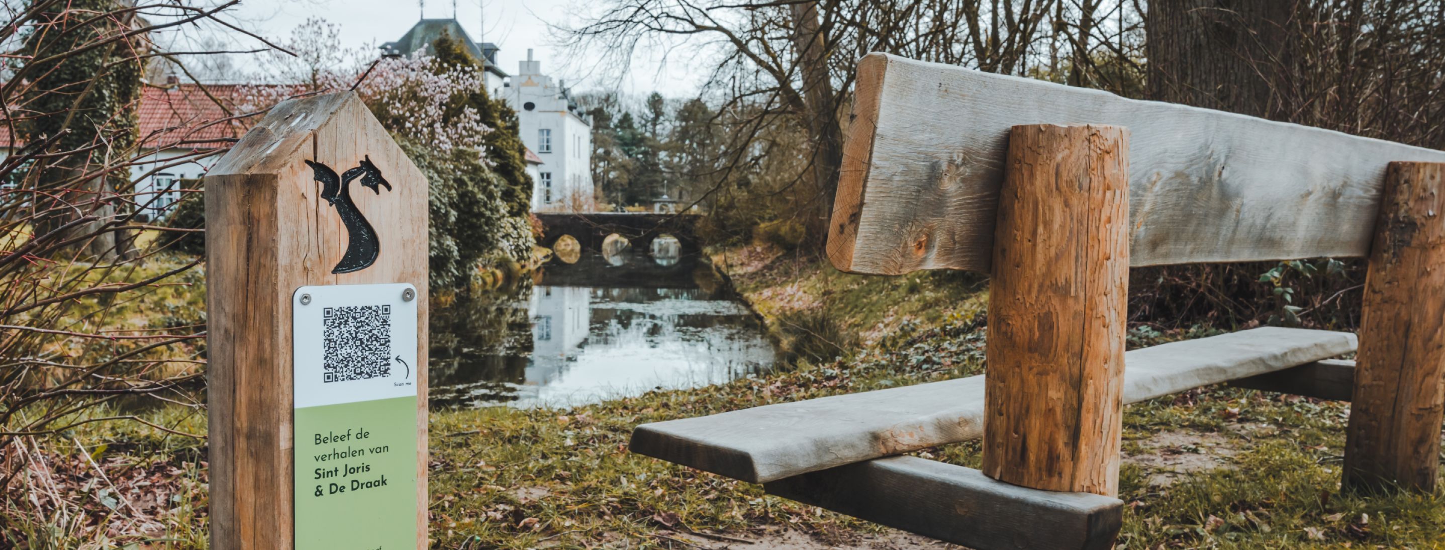 Bankje langs het water in Beesel met QR-routepaal van de Erfgoed Route, waar je via je telefoon de legende van Sint Joris en de Draak beleeft