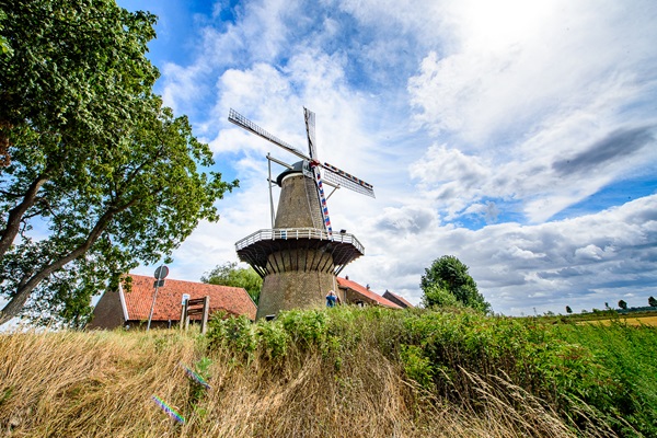 De Hompesche Molen op een bewolkte zomerdag met een meneer die een foto maakt van de molen