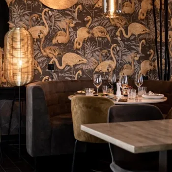 Sfeervol gedekte tafel in Riverside Lounge in Maasbracht, met warm interieur en decoratieve flamingo-behang, ideaal voor een ontspannen herfstlunch aan het water.