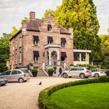 Kasteeltje Hattem in Roermond, een statig landhuis met luiken en oprijlaan, omgeven door groen en geparkeerde auto’s op het grindpad.